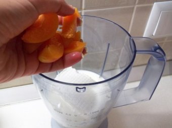 Молоко налейте в блендер,  положите мороженное и абрикосы.